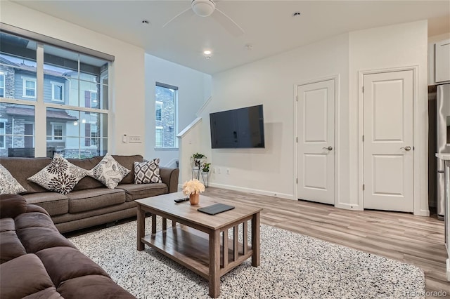 living area with light wood-type flooring, a ceiling fan, baseboards, and recessed lighting