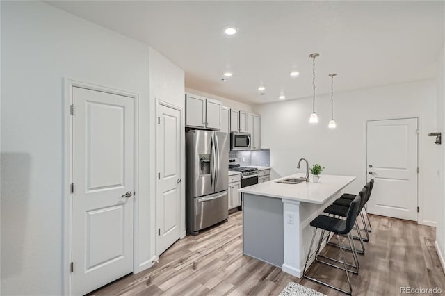kitchen with stainless steel appliances, light wood-style flooring, a kitchen bar, a sink, and recessed lighting