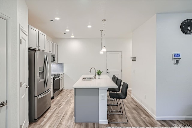 kitchen with appliances with stainless steel finishes, a sink, light wood-style flooring, a breakfast bar, and recessed lighting