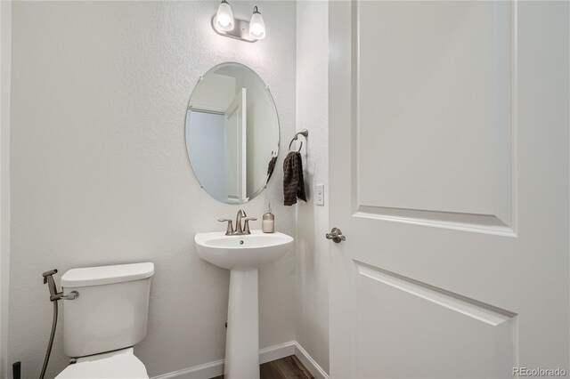 bathroom with toilet, a sink, and wood finished floors