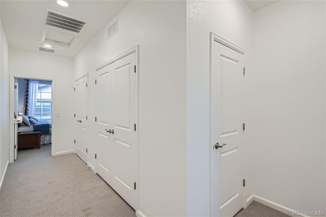 hallway featuring light colored carpet and baseboards