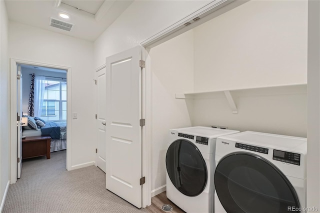 clothes washing area with washing machine and clothes dryer, light colored carpet, and baseboards