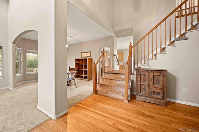 10170 E 151st Ct, Brighton, CO 80602 - stairway featuring arched walkways, wood finished floors, baseboards, a towering ceiling, and carpet