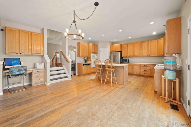 10170 E 151st Ct, Brighton, CO 80602 - kitchen featuring appliances with stainless steel finishes, a kitchen breakfast bar, a kitchen island, light wood finished floors, and light countertops