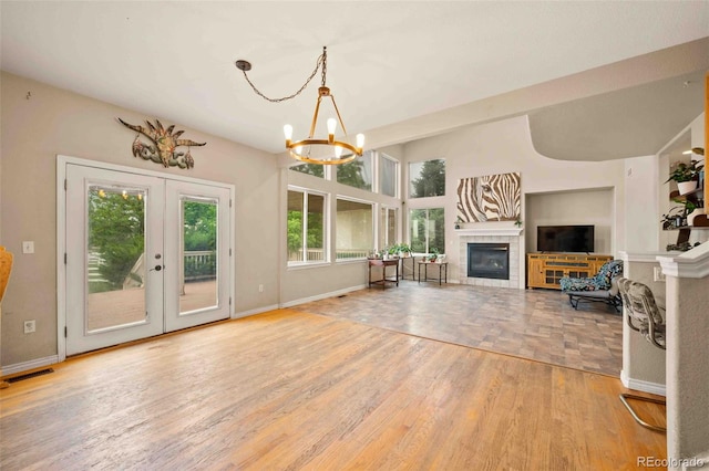 10170 E 151st Ct, Brighton, CO 80602 - unfurnished living room with a chandelier, a tile fireplace, baseboards, french doors, and wood finished floors