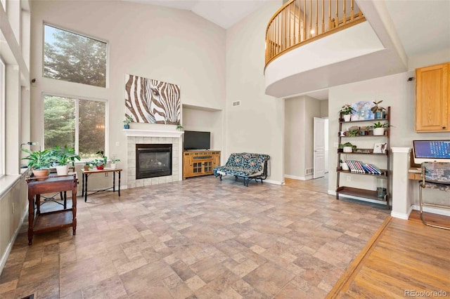 10170 E 151st Ct, Brighton, CO 80602 - living room featuring a high ceiling, a fireplace, light stone finish flooring, and baseboards