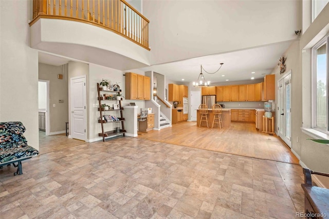 10170 E 151st Ct, Brighton, CO 80602 - kitchen featuring freestanding refrigerator, light stone finish flooring, a high ceiling, a center island, and a chandelier