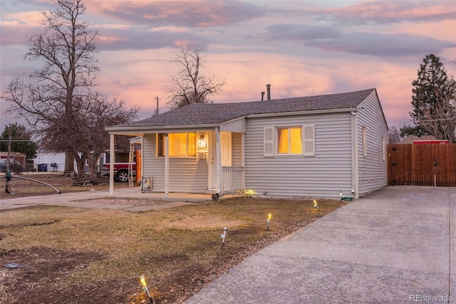 view of front facade featuring a yard, a shingled roof, and fence