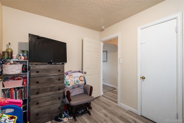 bedroom featuring a textured ceiling, wood finished floors, and baseboards