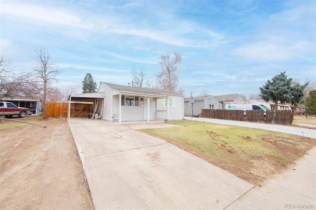 view of front of home with a carport, fence, concrete driveway, and a front yard