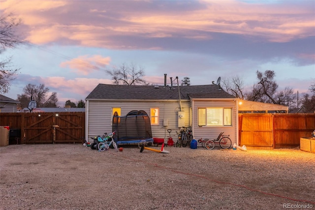 back of house featuring a trampoline, fence, and a gate