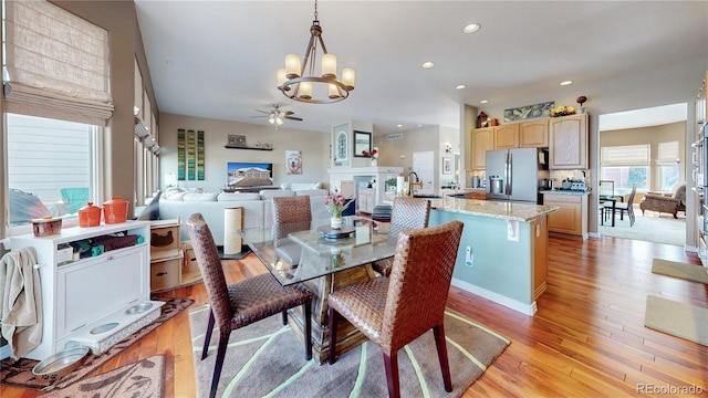 dining space featuring ceiling fan with notable chandelier, light wood finished floors, a fireplace, and recessed lighting