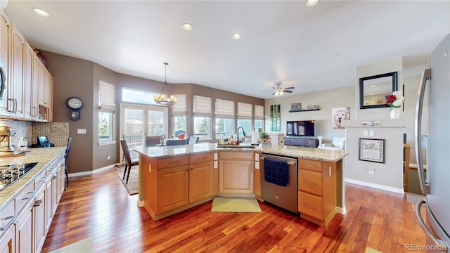 kitchen featuring light wood-style flooring, open floor plan, appliances with stainless steel finishes, decorative backsplash, and light brown cabinetry