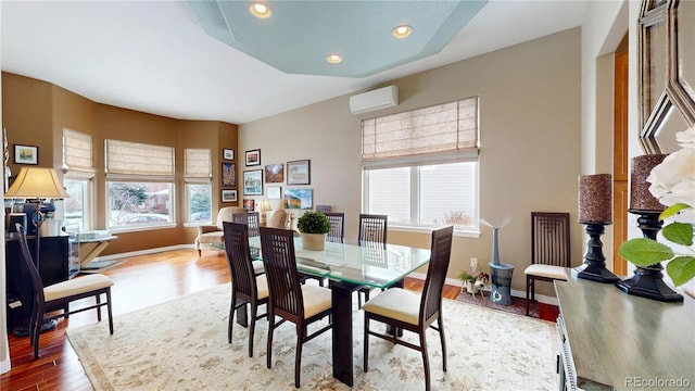 dining room featuring baseboards, a wall unit AC, wood finished floors, and recessed lighting