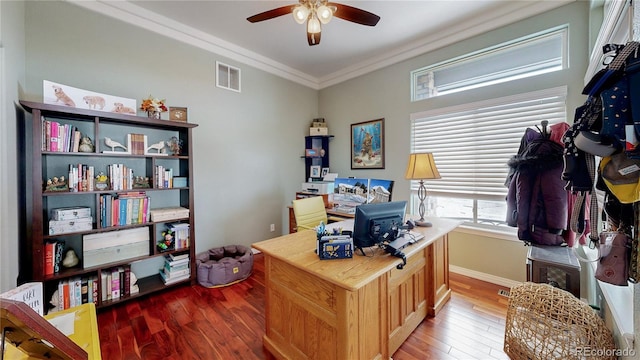 office area featuring wood finished floors, a ceiling fan, baseboards, visible vents, and crown molding