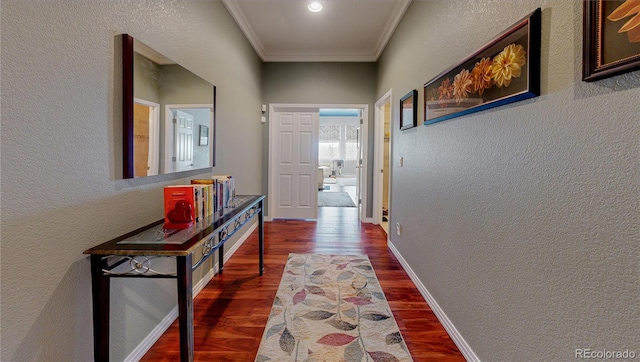 hall featuring a textured wall, crown molding, baseboards, and wood finished floors