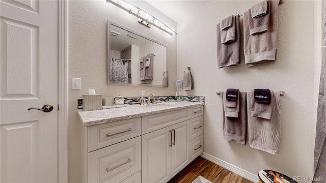 full bath with baseboards, wood finished floors, and vanity