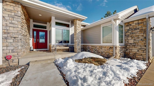 view of exterior entry with stone siding and a porch