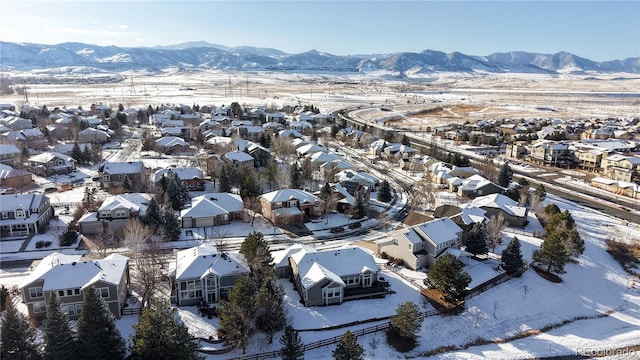 snowy aerial view featuring a mountain view and a residential view