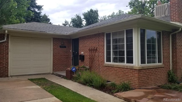 exterior space featuring driveway, brick siding, and an attached garage