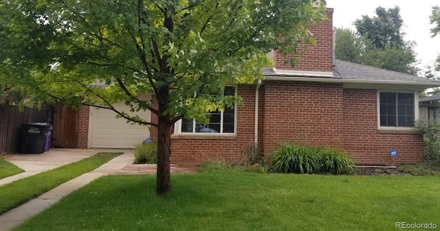 view of home's exterior with fence, a yard, concrete driveway, brick siding, and a chimney