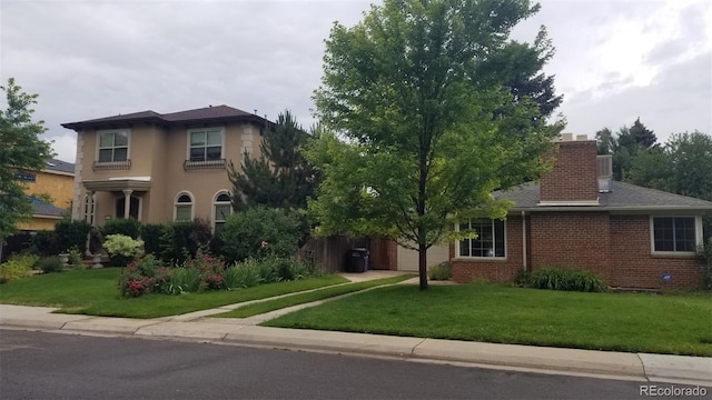 view of front of property featuring brick siding, a garage, a chimney, and a front yard