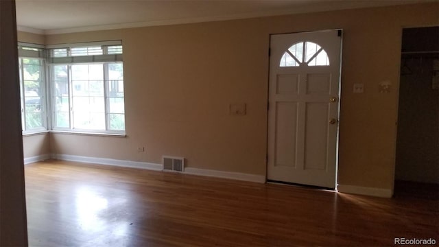 foyer entrance featuring crown molding, wood finished floors, visible vents, and baseboards