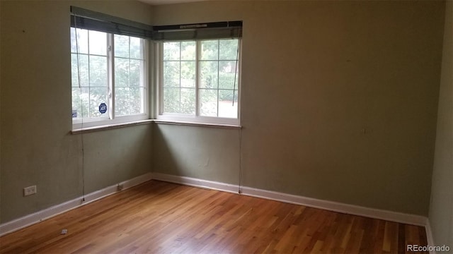 spare room featuring baseboards and wood finished floors