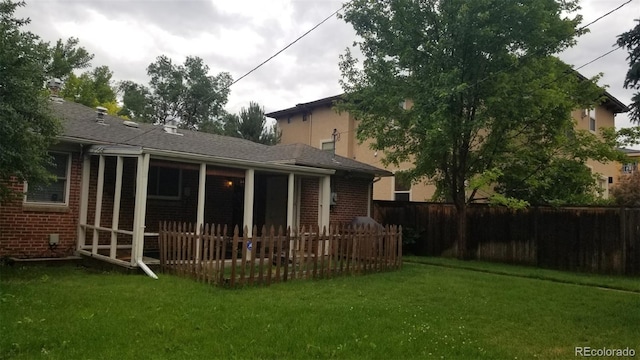 back of property with a lawn, brick siding, and fence