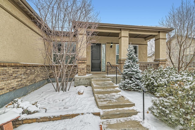 snow covered property entrance with a porch