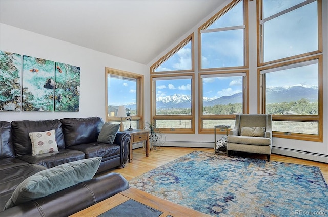 living room with a baseboard radiator, lofted ceiling, a mountain view, and light hardwood / wood-style floors