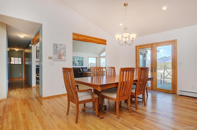 dining room with lofted ceiling, a wealth of natural light, an inviting chandelier, and light wood-type flooring