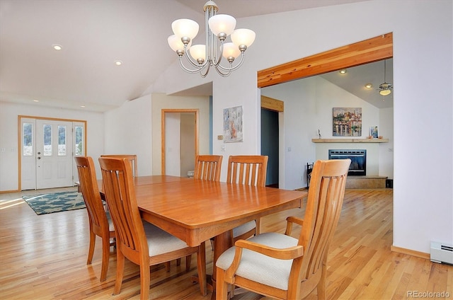 dining space featuring vaulted ceiling, a chandelier, light hardwood / wood-style floors, and baseboard heating