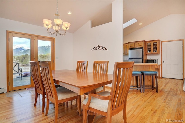 dining space featuring an inviting chandelier, light hardwood / wood-style floors, and vaulted ceiling