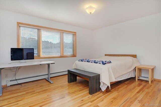 bedroom with baseboard heating, light hardwood / wood-style floors, and multiple windows