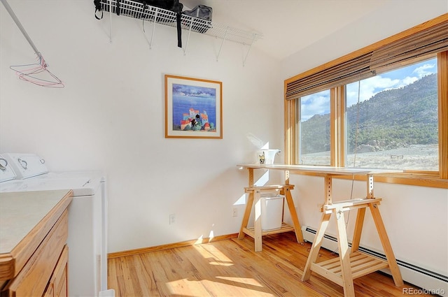 laundry area featuring cabinets, light hardwood / wood-style floors, washer and dryer, and a baseboard heating unit