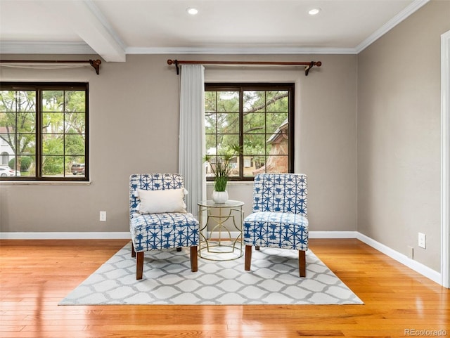 sitting room featuring a wealth of natural light, light hardwood / wood-style flooring, crown molding, and beamed ceiling