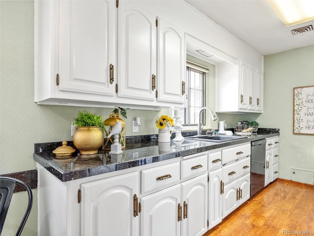 kitchen featuring light wood-type flooring, stainless steel dishwasher, and white cabinetry