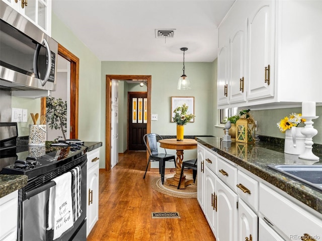 kitchen with decorative light fixtures, range, light wood-type flooring, and white cabinetry