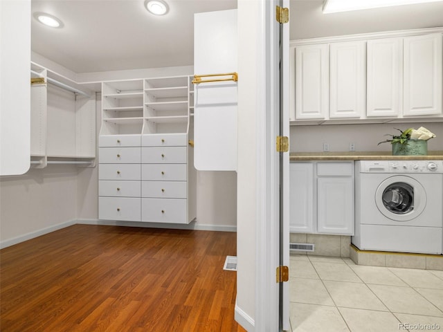 laundry room featuring light hardwood / wood-style floors, washer / dryer, and cabinets