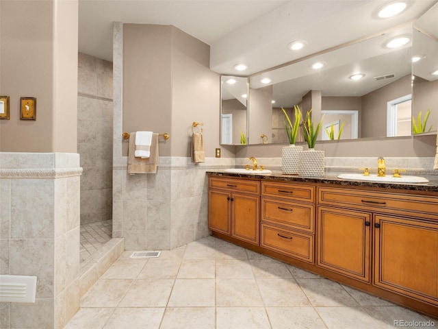 bathroom featuring tile patterned flooring, a tile shower, and vanity