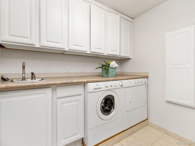 clothes washing area featuring sink, light tile patterned floors, separate washer and dryer, and cabinets