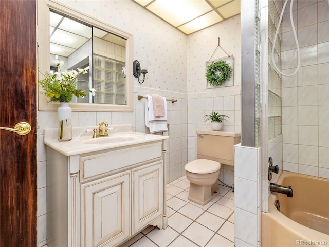 full bathroom featuring tiled shower / bath, tile walls, tile patterned flooring, vanity, and toilet