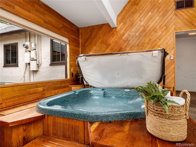 exterior space featuring beam ceiling, a jacuzzi, and wood walls