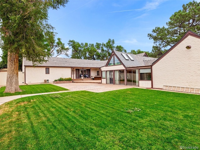 rear view of house with a sunroom, a patio, and a lawn