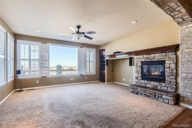 unfurnished living room featuring a fireplace, a textured ceiling, carpet floors, and ceiling fan