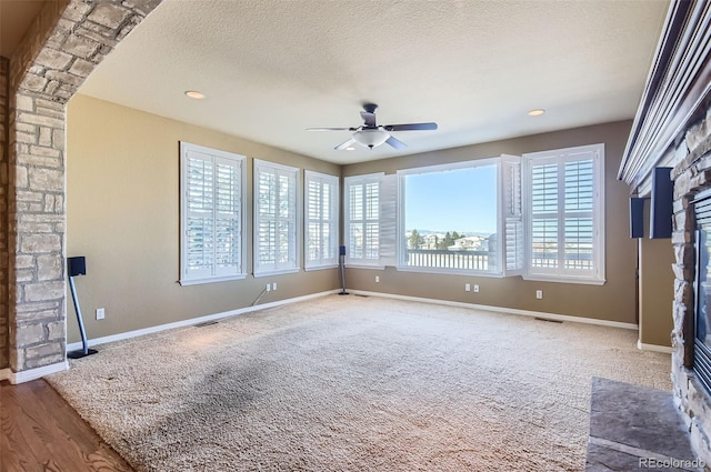 unfurnished room featuring ceiling fan, a fireplace, wood-type flooring, and a textured ceiling