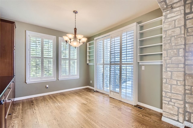 unfurnished dining area featuring a notable chandelier and wood-type flooring