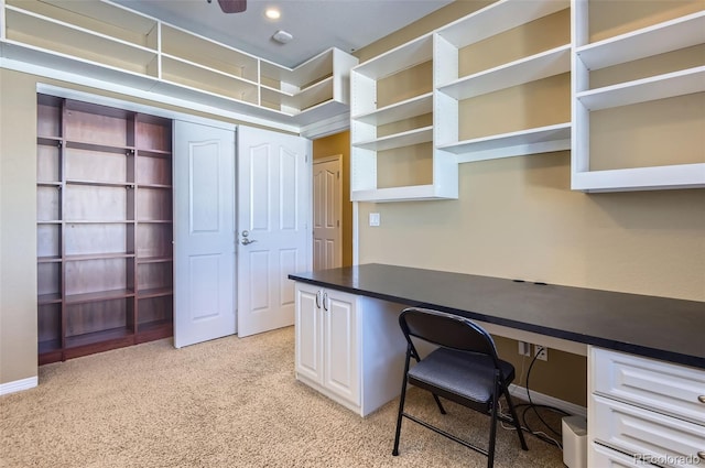 carpeted office with ceiling fan and built in desk