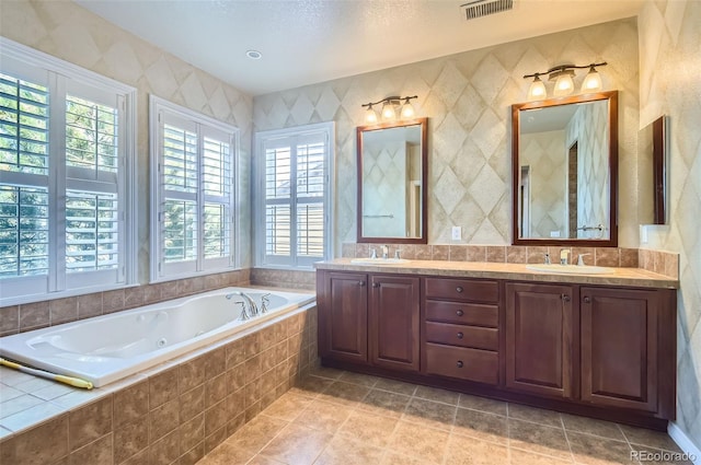 bathroom with tiled tub, tile patterned flooring, and vanity